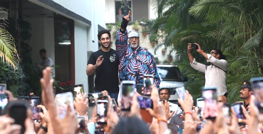 A man and an older man with a beard and glasses posing together at an outdoor event.