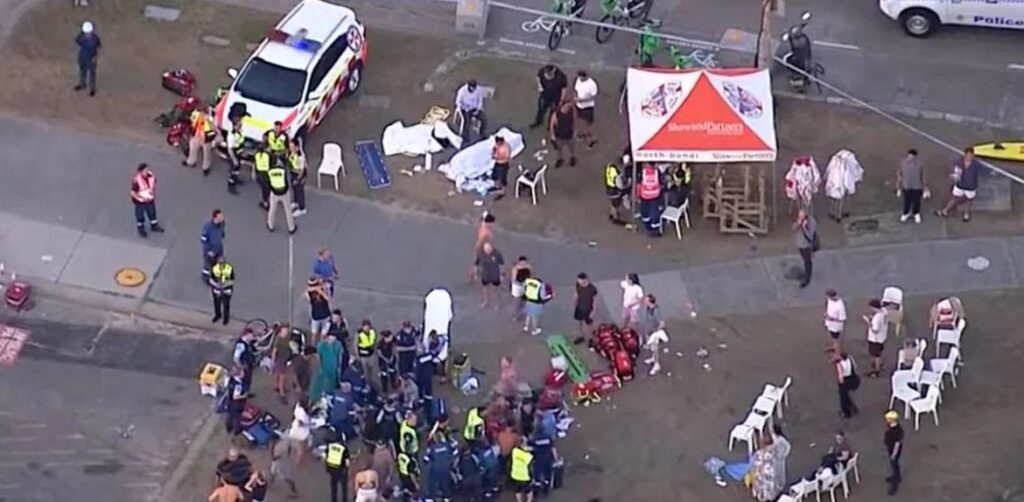Emergency responders attending to an accident scene with injured people and bystanders on the street.
