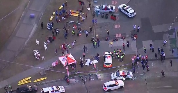 Aerial view of a busy street scene with pedestrians and vehicles in an urban area.