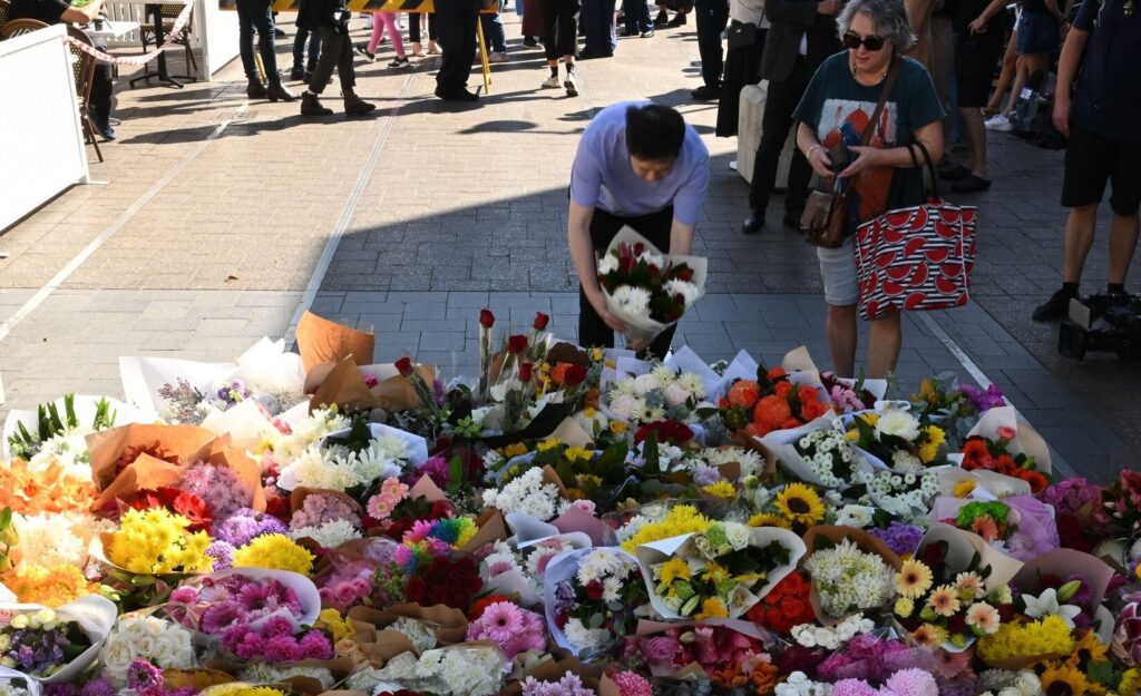A colorful array of flowers laid on the ground for a memorial or tribute.
