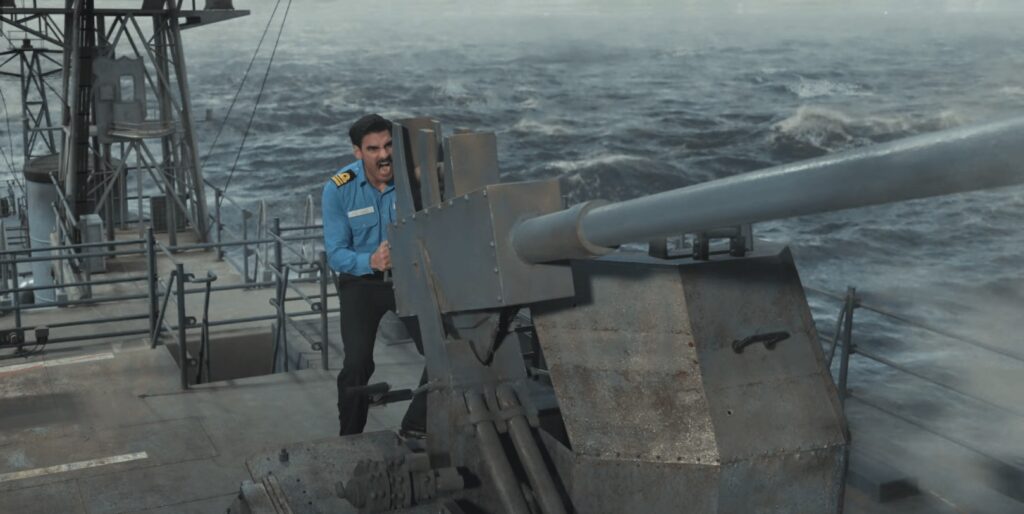 A man operating a large naval gun on a ship at sea.