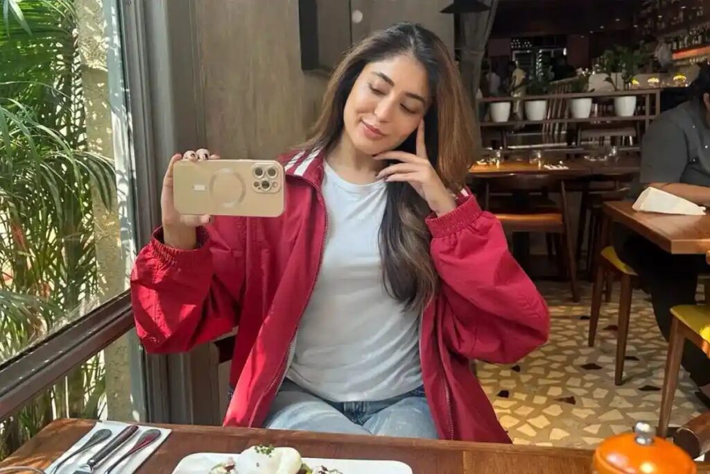 A woman taking a selfie at a restaurant table, enjoying her meal and capturing the moment.