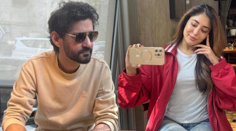 Man and woman taking a selfie indoors, casual attire, smiling, modern setting.