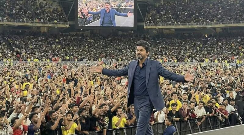 A man in a suit addressing a large crowd at a stadium event.