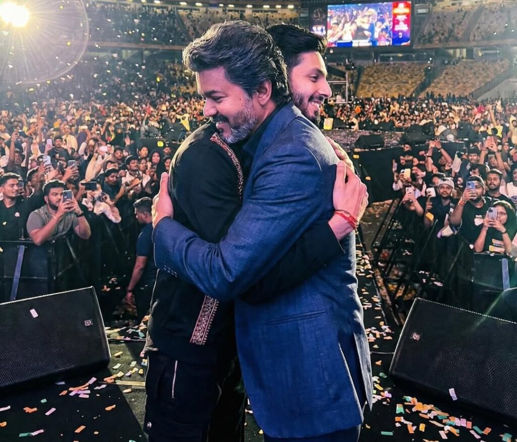Hugging men at a concert or event with a large crowd in the background, vibrant lighting, and a live.