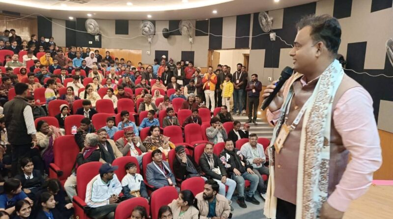 Engaging speaker addressing a large audience at SOOCHNA TANTRA event in an auditorium.