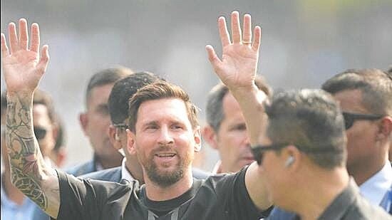 A man with a beard raising his hands in a crowd at an outdoor event.