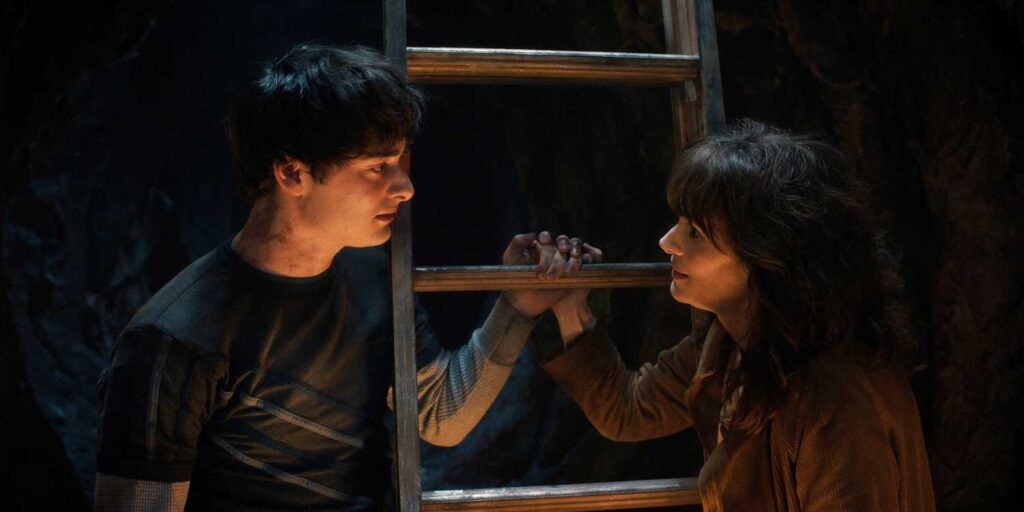 A young man and woman facing each other in a dramatic scene with a ladder between them.