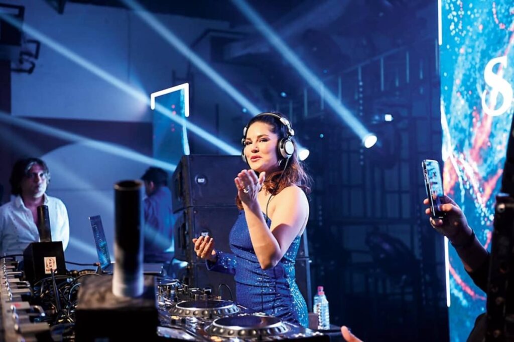 A woman DJ performing at a nightclub with colorful lighting and a lively atmosphere.