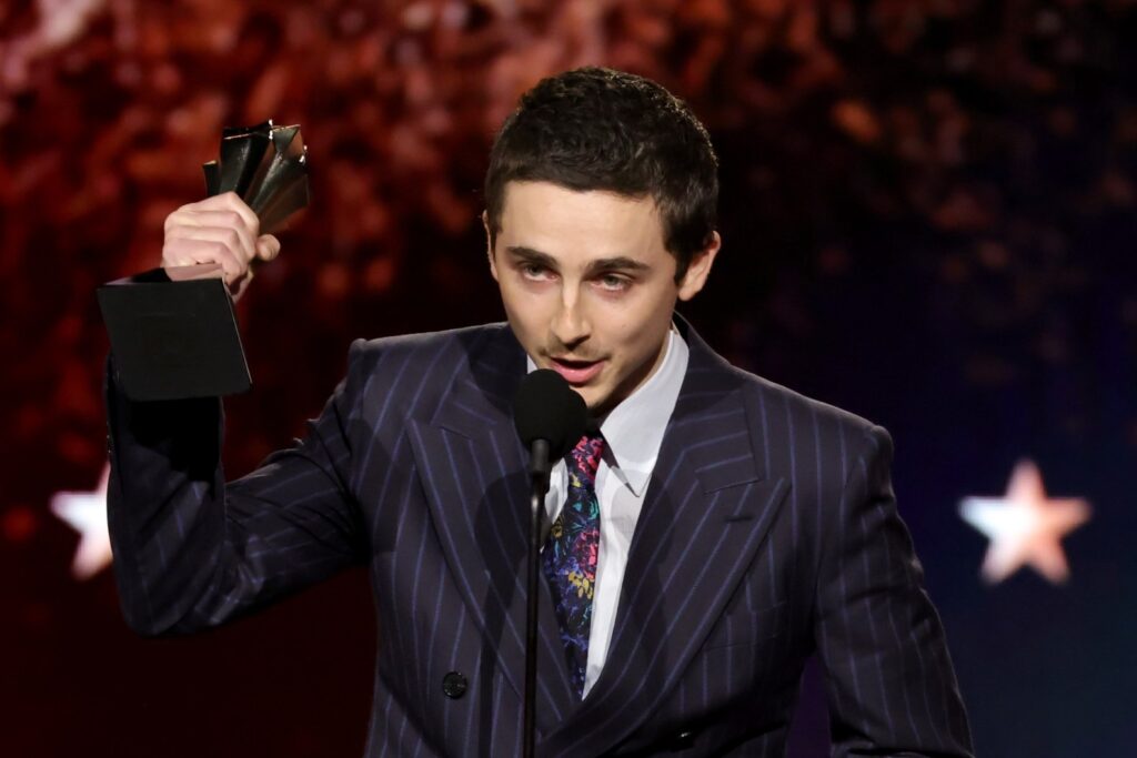 Man in suit holding award trophy at a formal event.