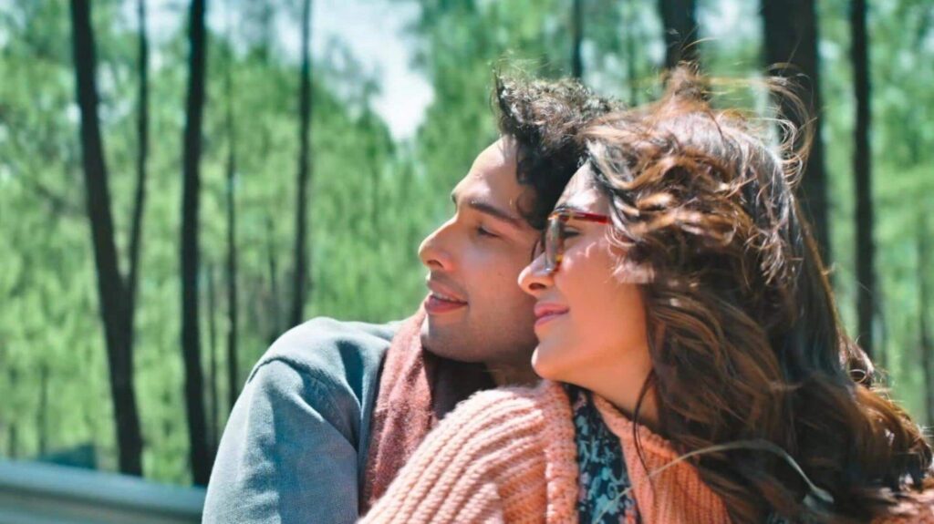 A woman and man enjoying a moment outdoors in a lush green forest setting.