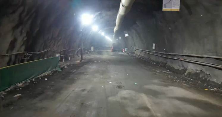 Tunneling construction site with rocky walls and road surface, showcasing underground infrastructure.