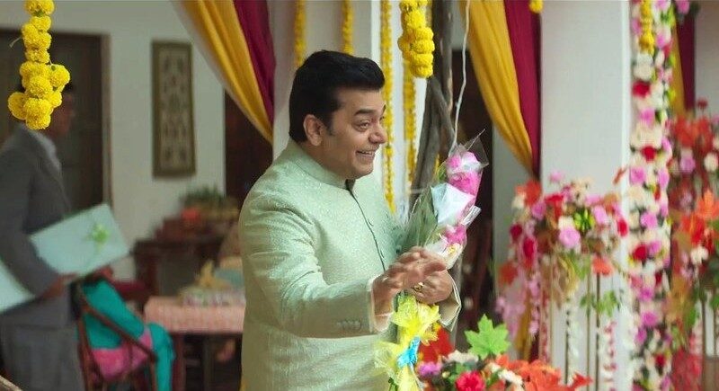A man celebrating a traditional Indian festival with flowers and decorations.